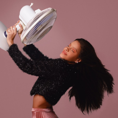 Young Female holding a fan above her blowing it down on herself