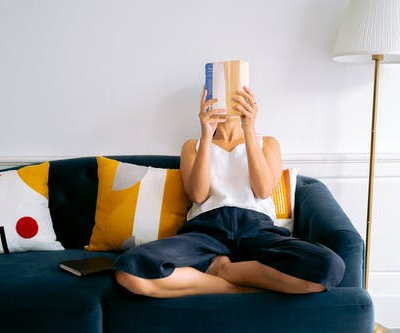 Women reading a book on the couch helping her mental health