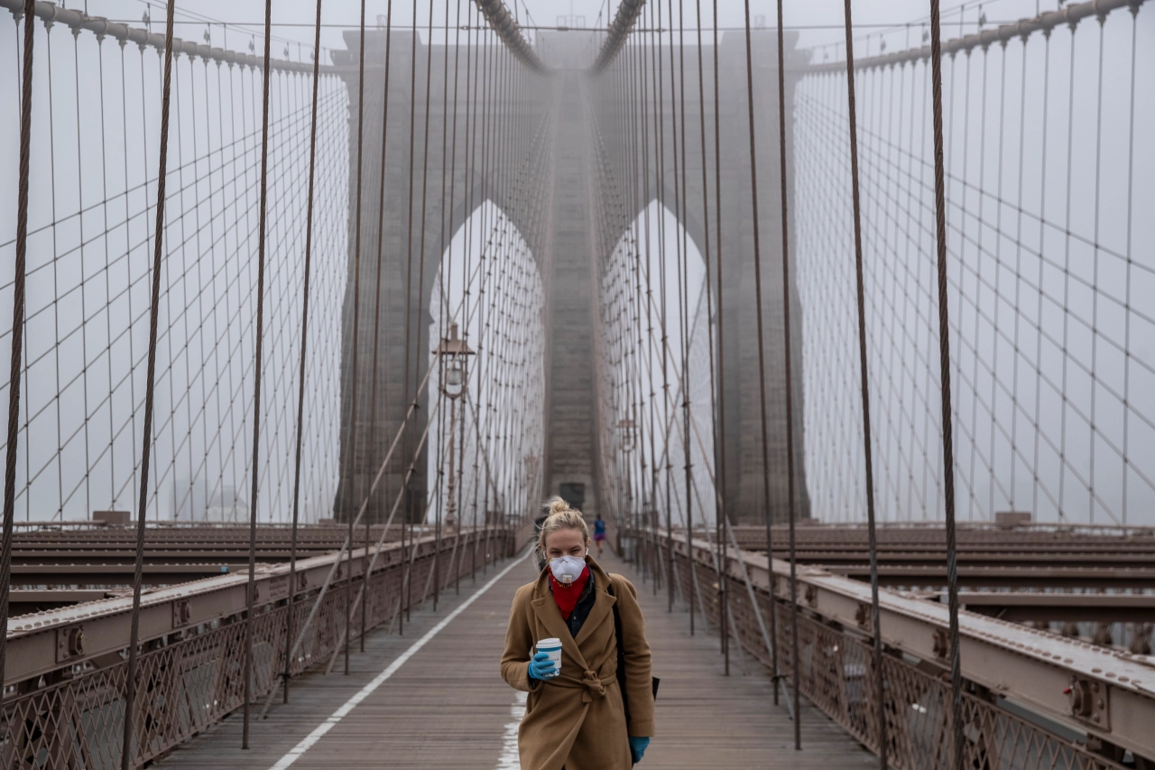 A woman wearing a mask walks the Brooklyn Bridge in the midst of COVID-19 outbreak.