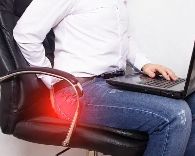 phot of a man seated in discomfort because of hemorrhoids.