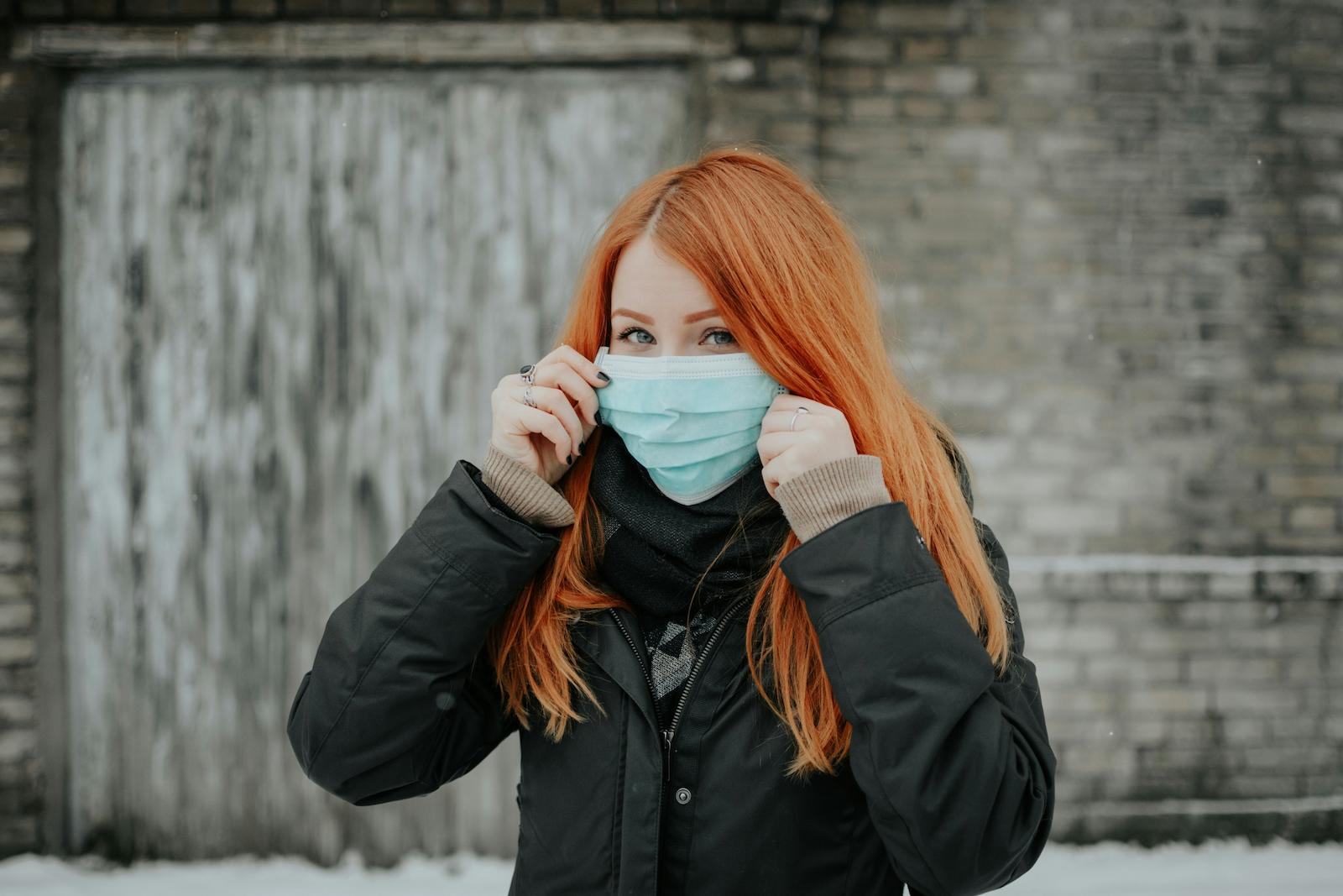 a photo of a woman holding a mask over her face, representing cold sores - treatable by a pharmacist in Orleans.