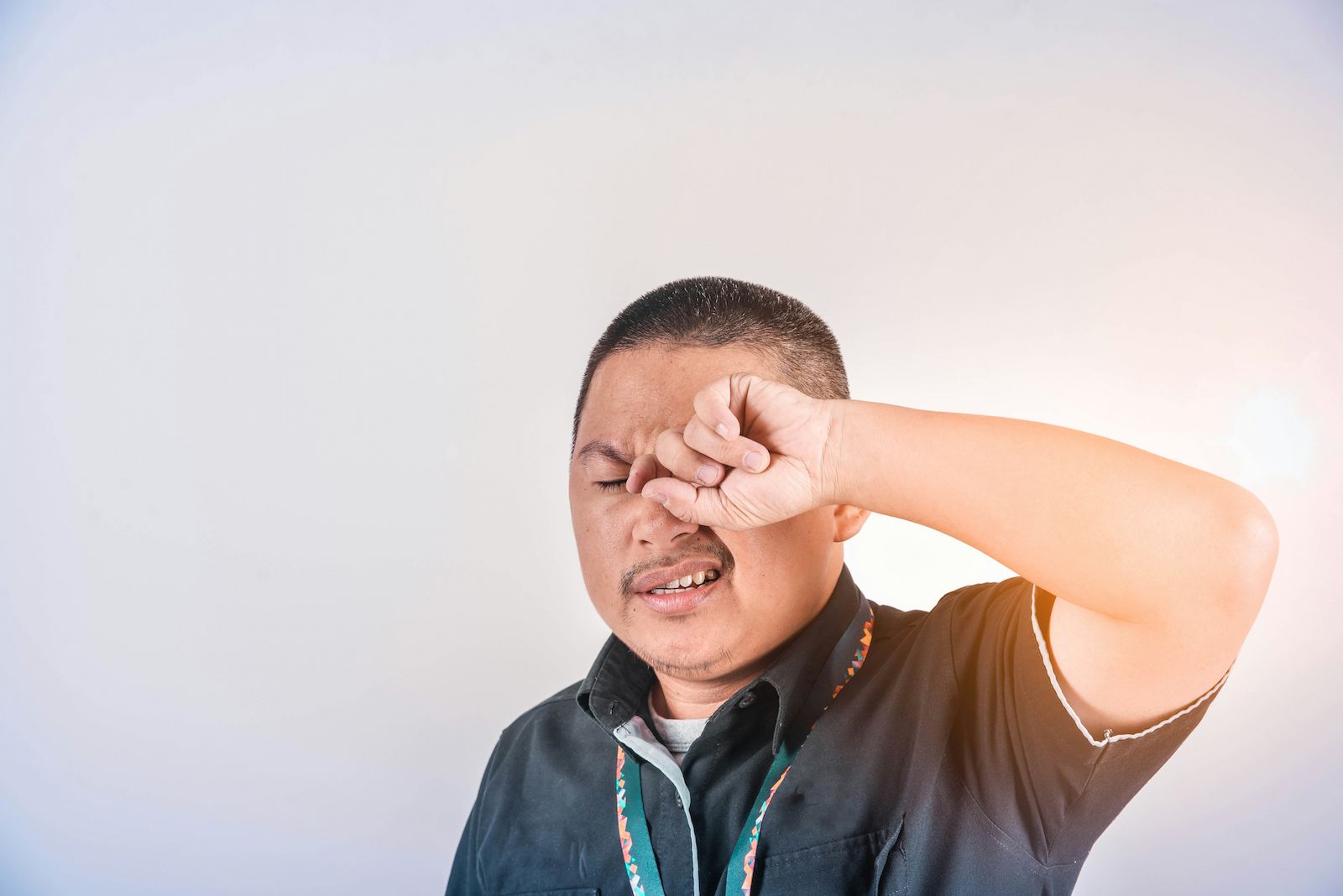 photo of an Ottawa man with pink eye rubbing his eyes. he is in need of minor ailment treatment from a Centrum Pharmacist in Orleans.