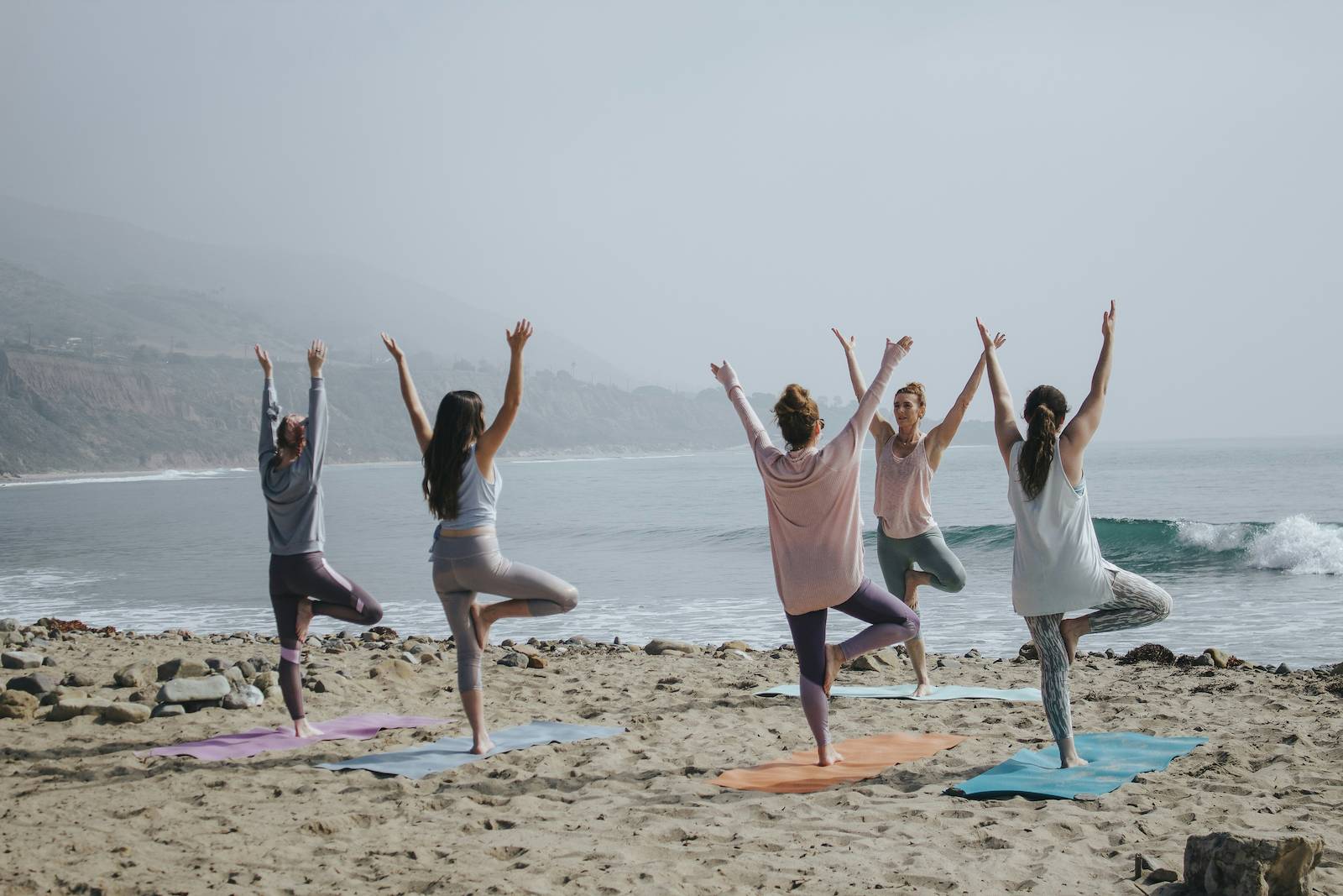 photo of 5 women on a beach practicing yoga.