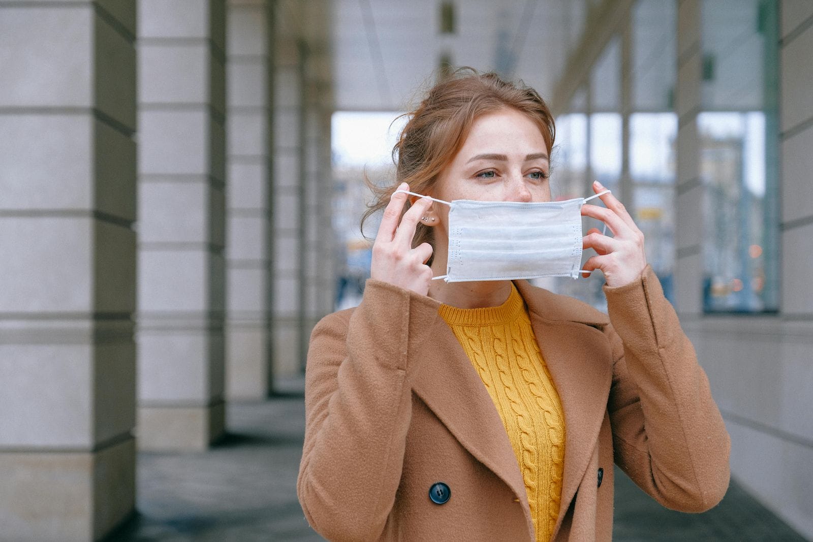 photo of a woman putting on a n95 mask - representing COVID-19 exposure which can be treated by a centrum pharmacist in Ottawa and Orleans.