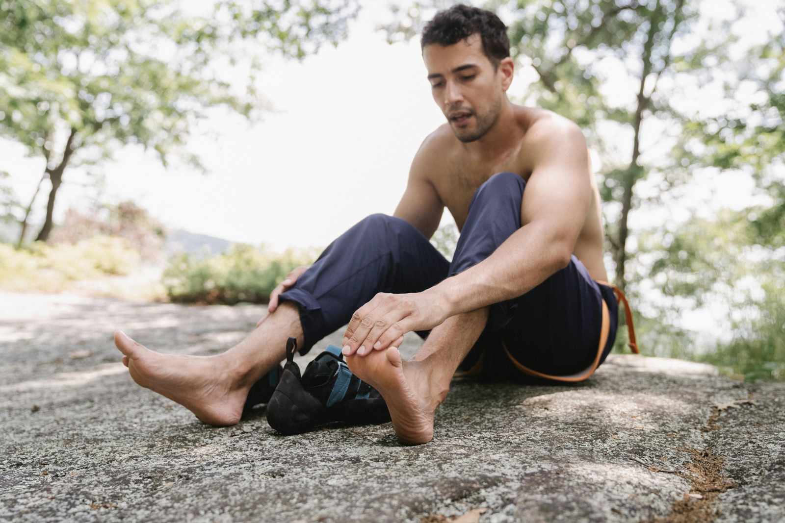 Orleans rock climber sitting assessing his foot for callus