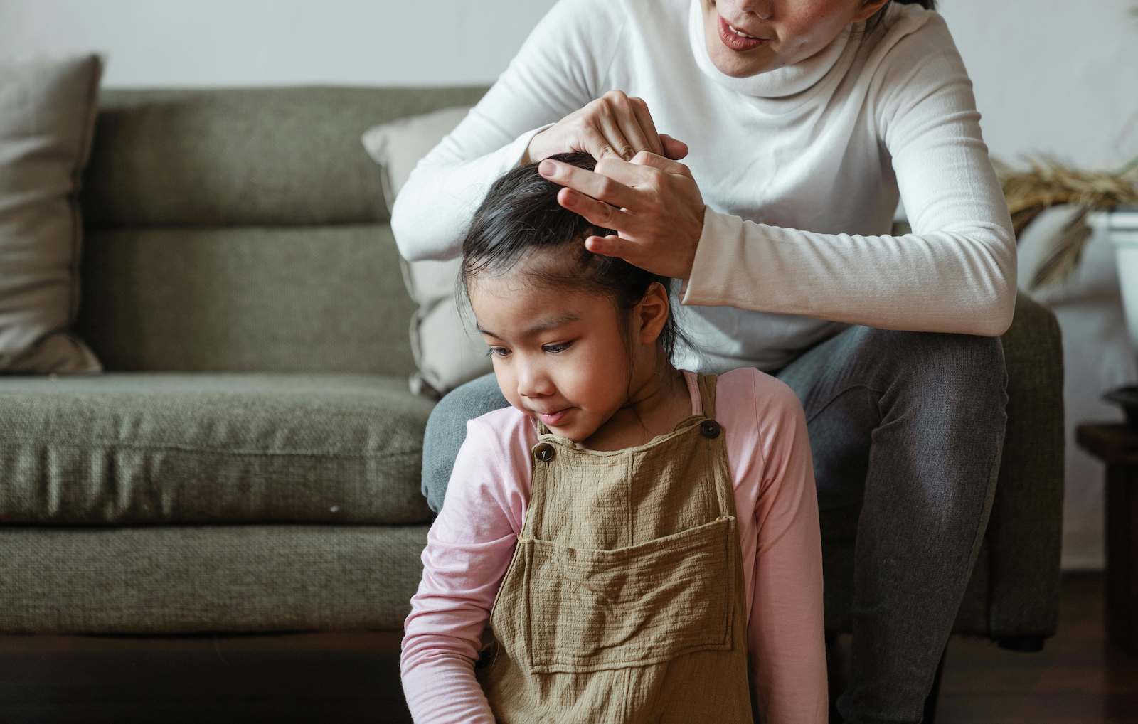 Woman checking her daughter's hair for head lice.
